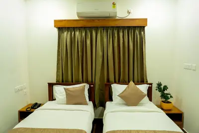 two beds in a room with a television on the wall at FLY VIEW Airport Residency in Nedumbassery