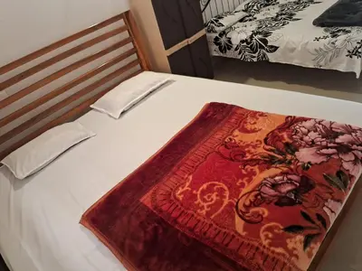 a bed with a red blanket on top of it at Shree Cottage in Madikeri