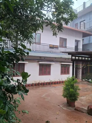 a white building with red windows and a courtyard at Shree Cottage in Madikeri