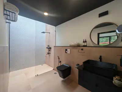 a bathroom with a shower and a sink and a mirror at Earthsong & Birdsong Luxury Pool Villa by Luxunlock Private Villas in Suntikoppa