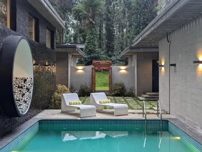 a swimming pool with two chairs and a house at Earthsong & Birdsong Luxury Pool Villa by Luxunlock Private Villas in Suntikoppa