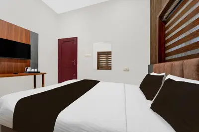 a bedroom with a large white bed with black pillows at Townhouse Thondayad Calicut Formerly Dream Casa in Kakkayam