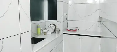a white tiled kitchen with a sink and a sink at Little home apartment in Kozhikode