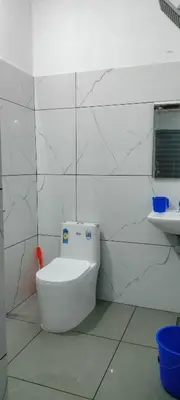 a white bathroom with a toilet and a sink at Little home apartment in Kozhikode