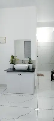 a white bathroom with a sink and a mirror at Little home apartment in Kozhikode