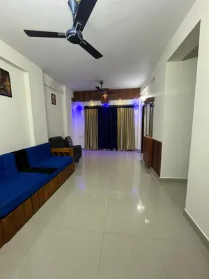 a living room with a blue couch and a ceiling fan at 1 BHK flat in Guruvayur - Sooryamadhavam Apartments-only for pilgrims in Guruvāyūr