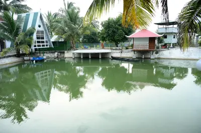 a body of water with palm trees and a building at Sidharth Resort, Vadavannur in Kollengode