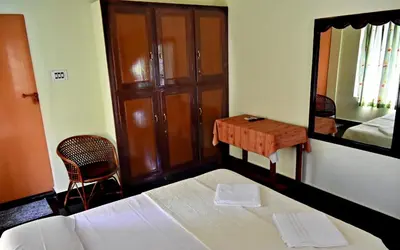 a bedroom with a bed and a table and a mirror at Ceema Homestay in Ernakulam