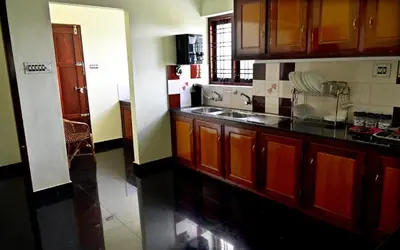 a kitchen with wooden cabinets and a counter top at Ceema Homestay in Ernakulam