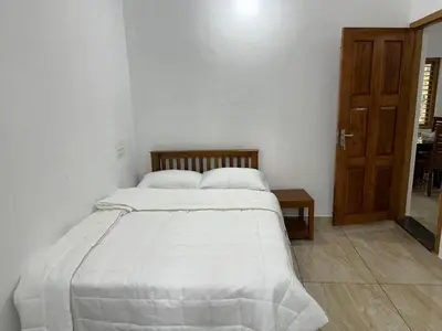 a white bed in a room with a wooden door at Serenity Home Stay in Sultan Bathery