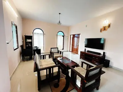 a living room with a table and a flat screen tv at Hilltown Villa Holiday's in Ooty