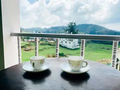 two coffee cups sitting on a table on a balcony at Hilltown Villa Holiday's in Ooty