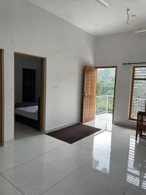 a room with a bed and a door with a balcony at aphrodite home stay in Pinangode