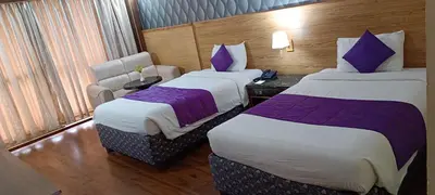 two beds in a hotel room with purple sheets at The Monarch in Ooty