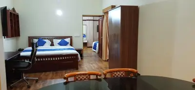 a bedroom with a bed and a desk and two chairs at The Monarch in Ooty