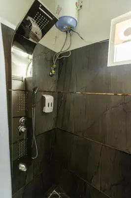 a bathroom with a shower with a black tiled wall at Bharath Pods in Coimbatore
