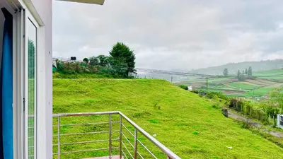 a view of a green hill from a window at Away From Home - 6 - Rooms In Ooty, Home Stay Ooty in Ooty