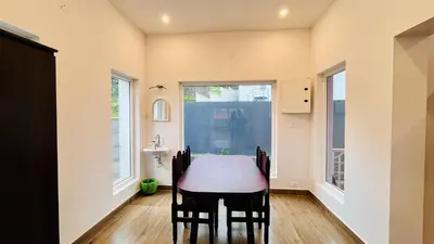 a dining room with a table and two windows at Away From Home - 6 - Rooms In Ooty, Home Stay Ooty in Ooty