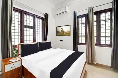a bedroom with a large bed with windows at Super Hotel O West Hill near Mietra Hospital in Calicut