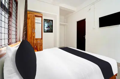 a bedroom with a white bed and a television at Super Hotel O West Hill near Mietra Hospital in Calicut