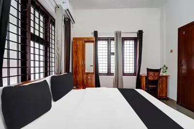 a bedroom with a black and white bed and windows at Super Hotel O West Hill near Mietra Hospital in Calicut