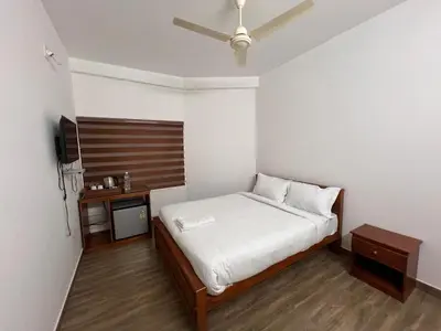 a small bedroom with a bed and a tv at Ashtapadi Inn in Guruvāyūr