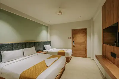 a hotel room with two beds and a television at Hotel Beverly Plaza Kozhikode in Kozhikode