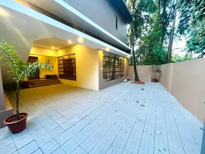 a large room with a white tiled floor in a house at Whitehouse homestay in Kannur