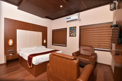 a bedroom with a bed and a couch and a chair at Garuda Luxury Bungalow in Trichūr