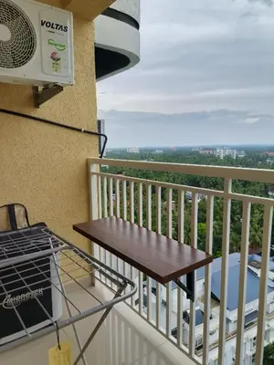 a balcony with a wooden table and a heater at Posh 1 BHK Apt with Temple View in Guruvayur C1301 in Guruvāyūr