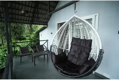 a hanging hammock with a chair on a porch at The Cozy Clouds Hill Stay in Napoklu