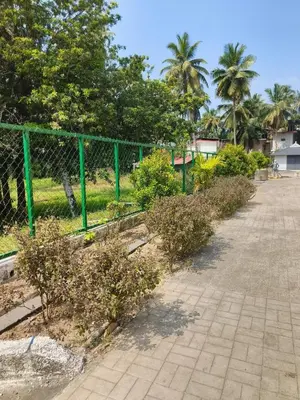 a walkway with a green fence and trees at Posh 1 BHK Apt with Temple View in Guruvayur B1001 in Guruvāyūr