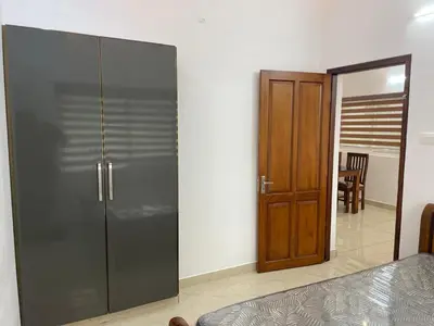 a bedroom with a large glass closet and a wooden door at RoyalGiri Apartment near Rajagiri Hospital in Alwaye
