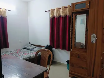 a bedroom with a bed and a dresser and a table at Home in kannur in Kannur
