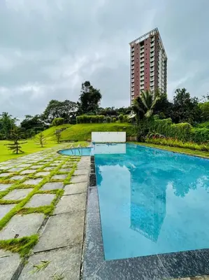 a swimming pool with a building in the background at Aaram Miraj Luxuria Apartment -1 in Wayanad