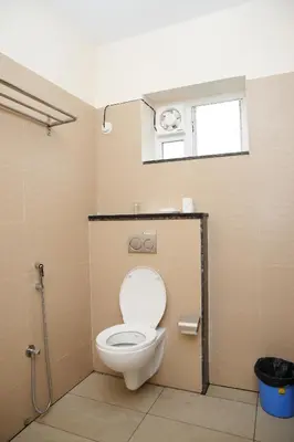 a bathroom with a toilet with a window at Hotel Orchard Coorg in Virajpet