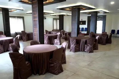 a banquet hall with tables and chairs in a room at Hotel Orchard Coorg in Virajpet