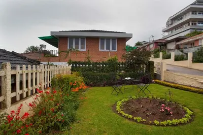 a garden in front of a house with a fence at Away From Home - 2 - Rooms In Ooty, Home Stay Ooty in Ooty