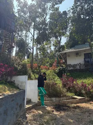 a man is leaning against a retaining wall at Lilliput Haven Homestay in Sultan Bathery