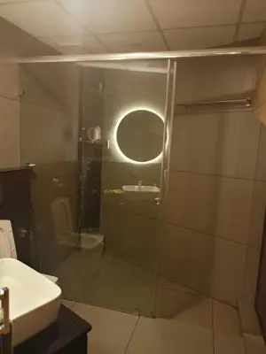 a bathroom with a glass shower and a sink at Green Haven Homestay in Kodungallūr