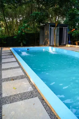 a swimming pool with blue water in a yard at Misty Hills Cabin in Wayanad