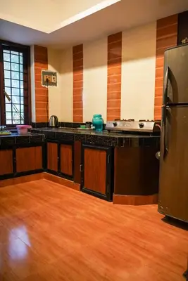 a kitchen with black counter tops and a refrigerator at Misty Hills Cabin in Wayanad