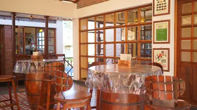 a restaurant with wooden chairs and tables and windows at Preserve Ooty in Ooty