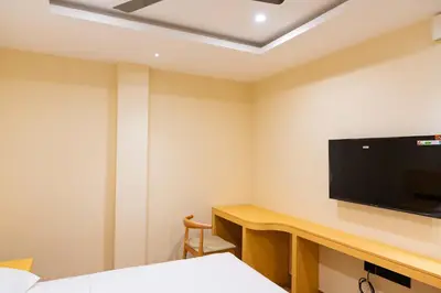 a room with a tv and a desk with a bed at The Paradise International Hotel in Coimbatore