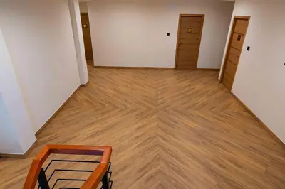 an empty room with a chair and wooden floors at The Paradise International Hotel in Coimbatore