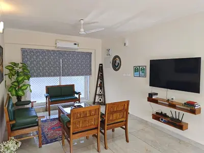 a living room with a tv and a table and chairs at 7 Elysee Homestay - Safire - Premium 3BHK Family Flat in Trichūr