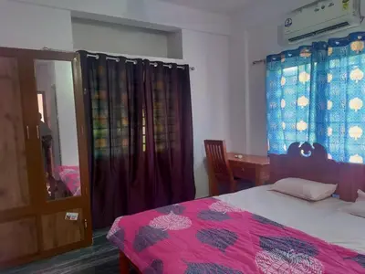 a bedroom with a bed and a table and a desk at Stay Castle in Guruvāyūr
