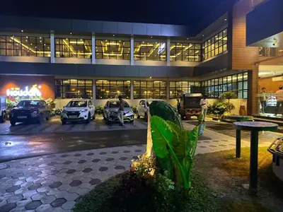 a large building with cars parked in a parking lot at Holidays Garden Resort in Kalpetta