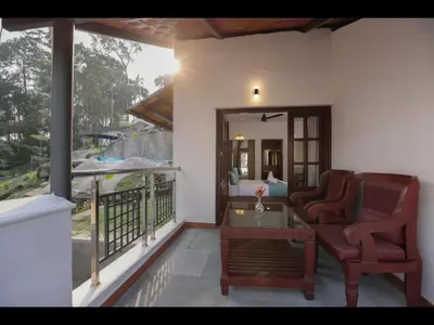 a balcony with two chairs and a table on a house at Holidays Garden Resort in Kalpetta