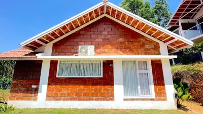 a red brick house with a white window at Monarda Resort in Padinjarathara